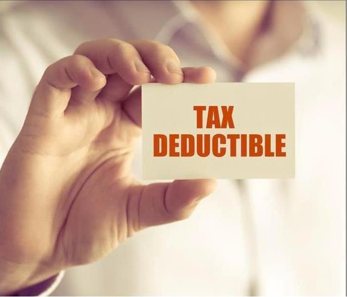 Hand holding a sign saying TAX DEDUCTIBLE