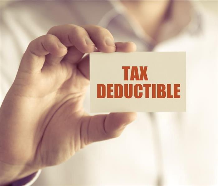 Closeup on businessman holding a card with text TAX DEDUCTIBLE