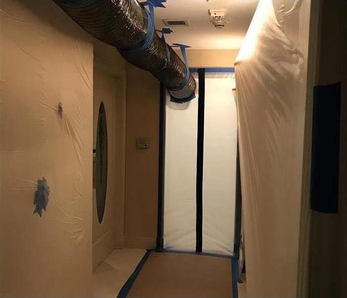 Walls covered with white plastic (mold containment), black hose hanging on ceiling (air chamber)